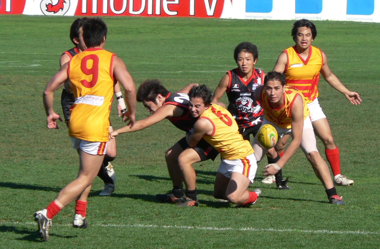 Player dispossessed of the ball in an Aussie Rules tackle.